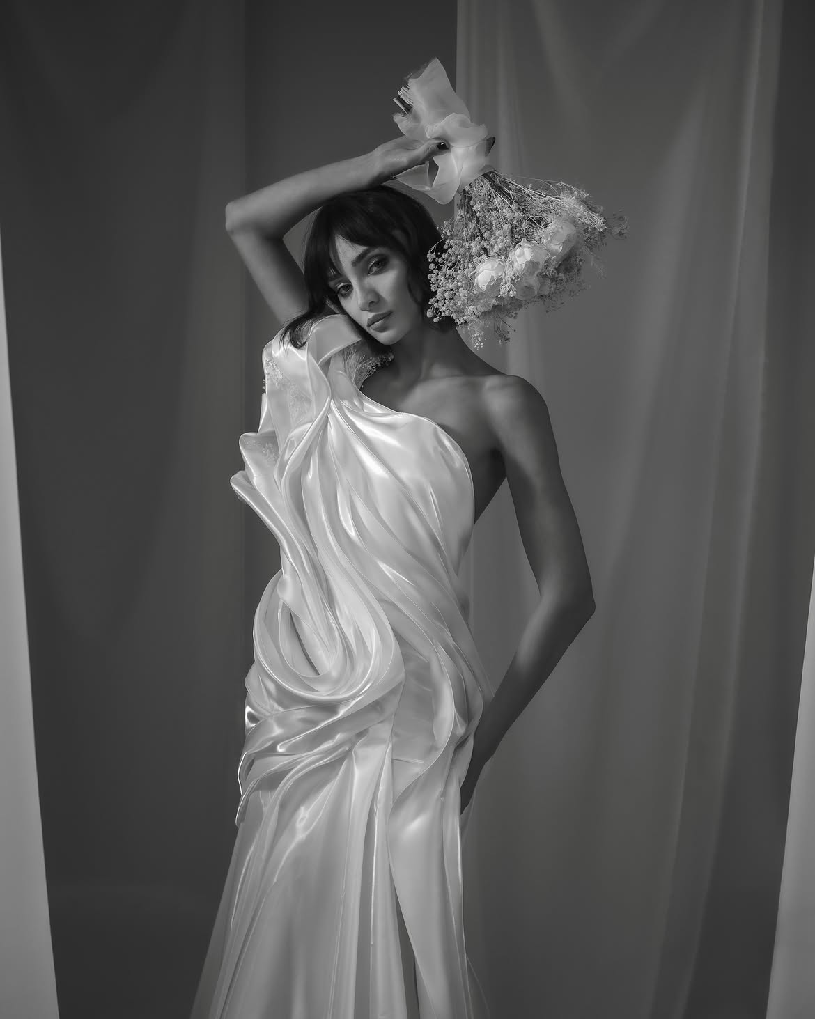 This dress has an elegant, sculptural feel with a strong emphasis on fluidity and texture. It ap